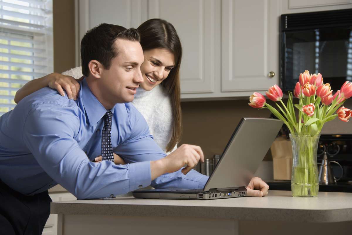 Couple using laptop in modern kitchen.