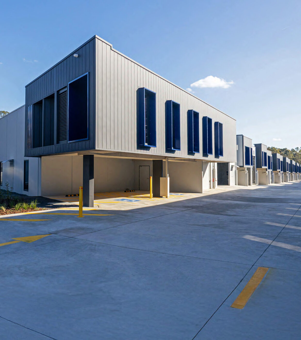 Modern industrial complex with accessible parking and large loading bays under clear blue skies.