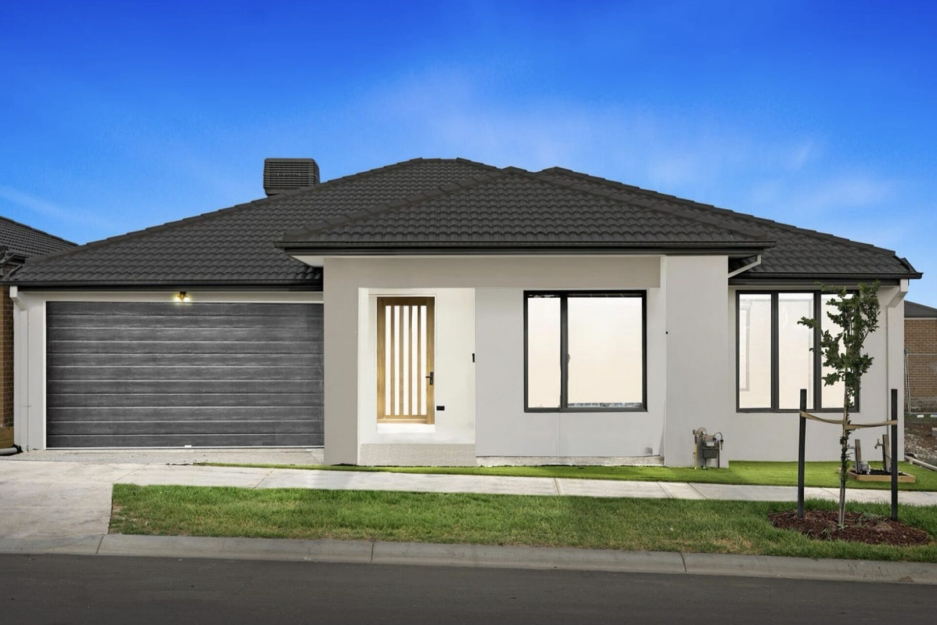 Modern single storey suburban house with double garage, sleek facade and landscaped front yard.